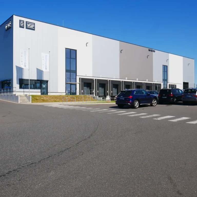 Isofit Lager Außenansicht Moderne Lagerhalle mit großen Fenstern und Parkplatz im Vordergrund.